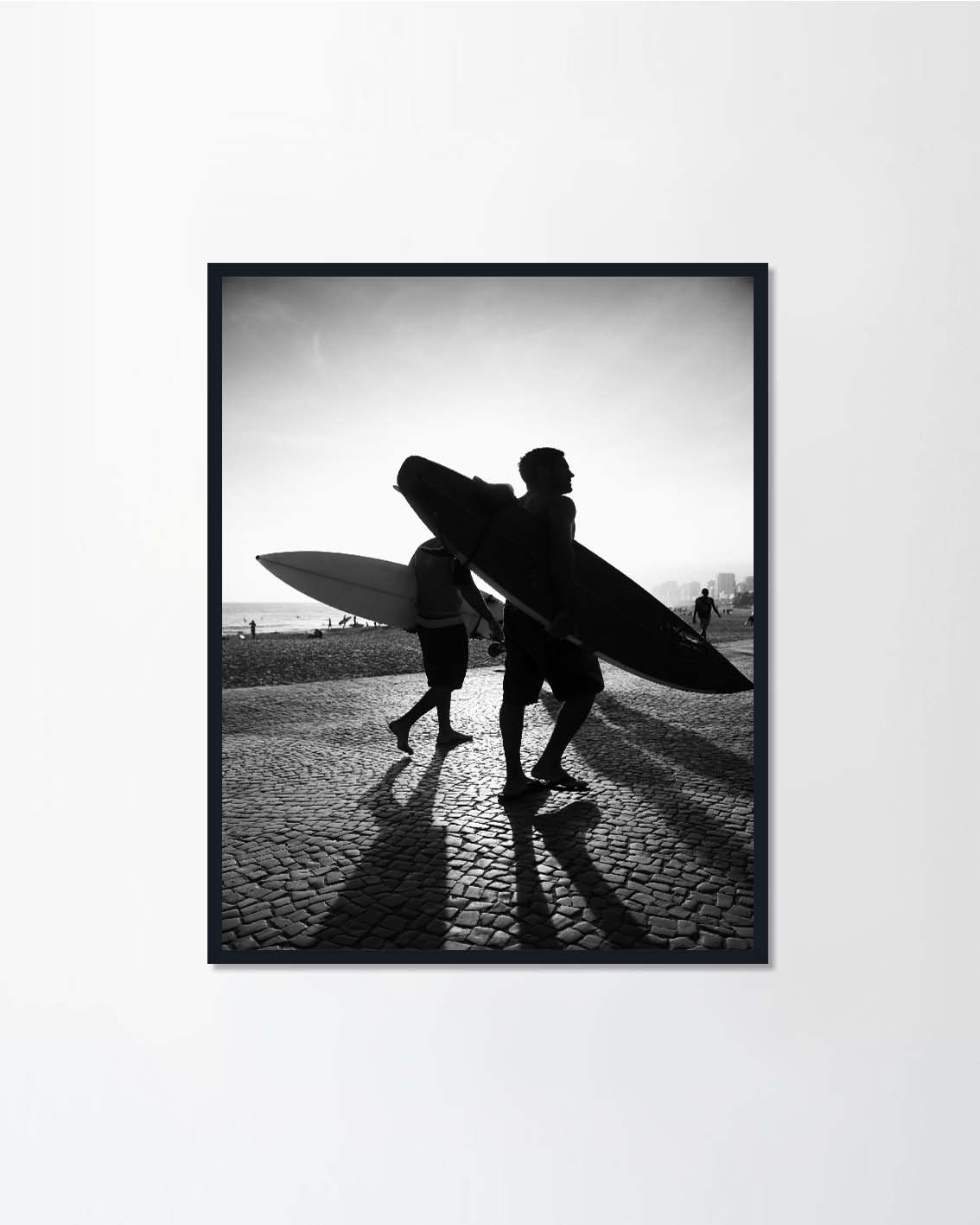 Sunset silhouettes of surfers walking
