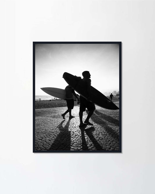 Sunset silhouettes of surfers walking