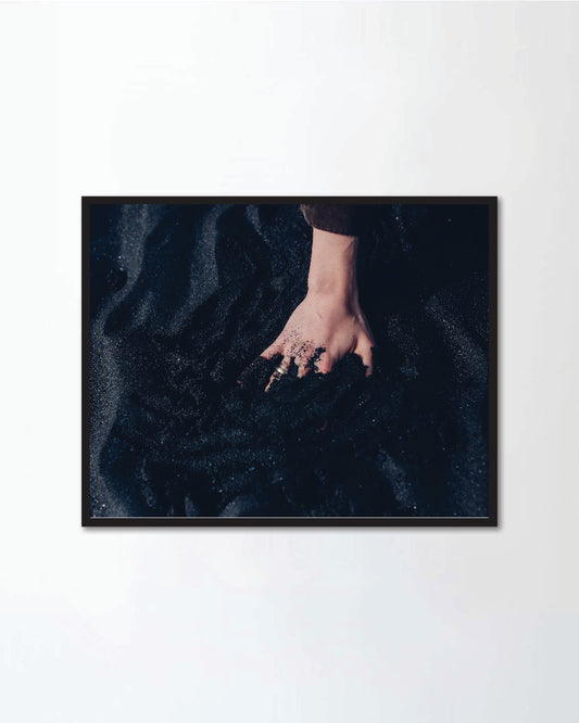 Hand with the ring in the black sand